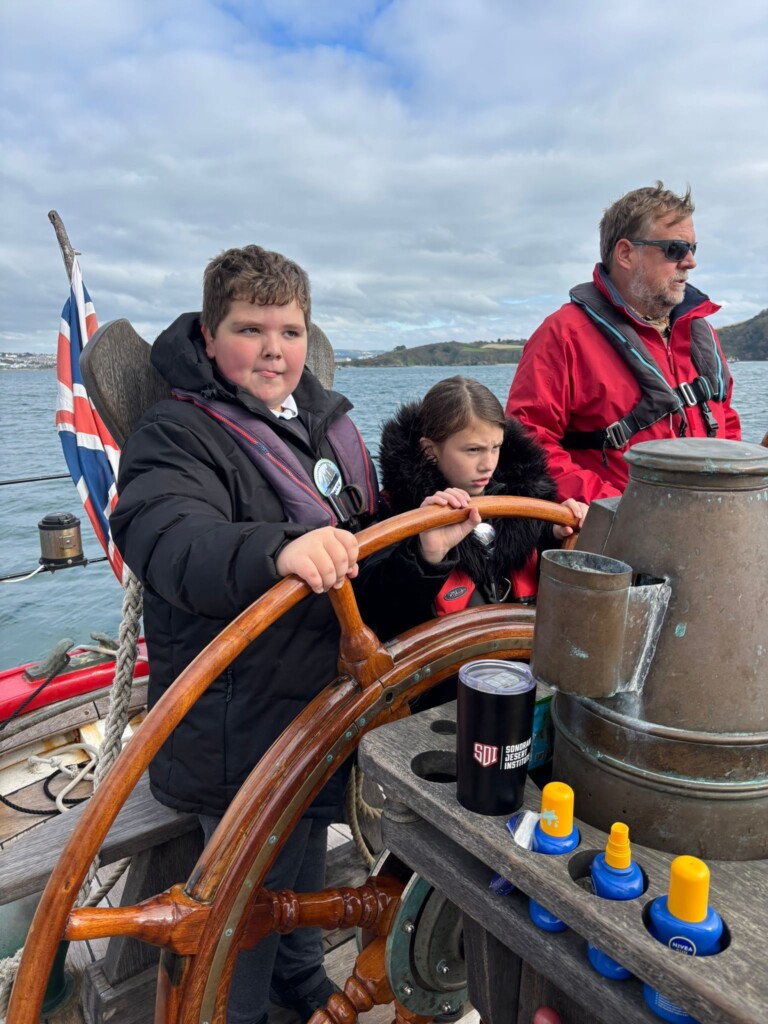 Marine Academy Pupils on a sailing boat, at the helm