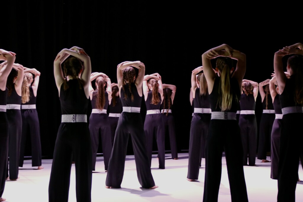 student dancers on stage with arms above their heads