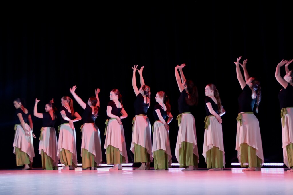 student dancers on stage with hands in the air