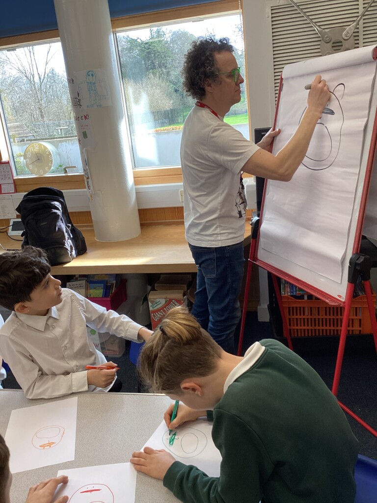 Alex Milway writing on a flip book in front of students in a class room. 
