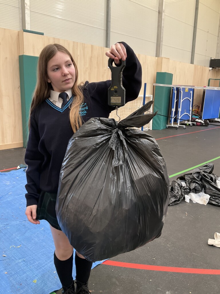 A student weighing a black bug full of rubbish. 