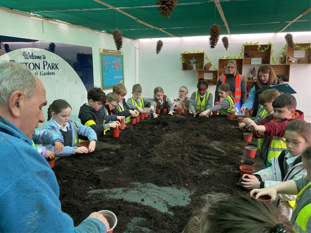 A group of students learning about and touching soil/compost.