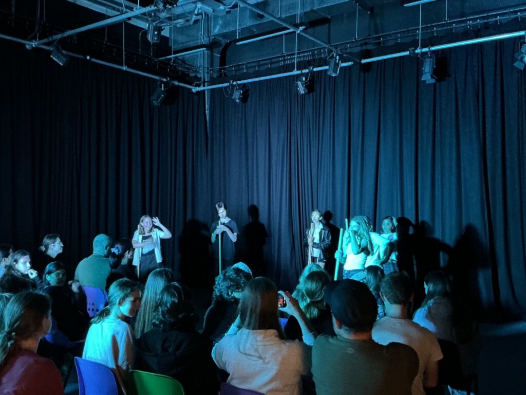 A group of students performing inside, with blue lighting. 