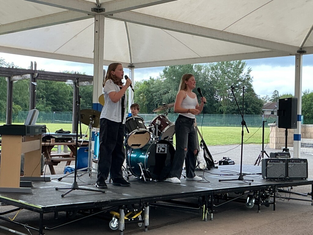 Two students singing and performing on an outdoor stage