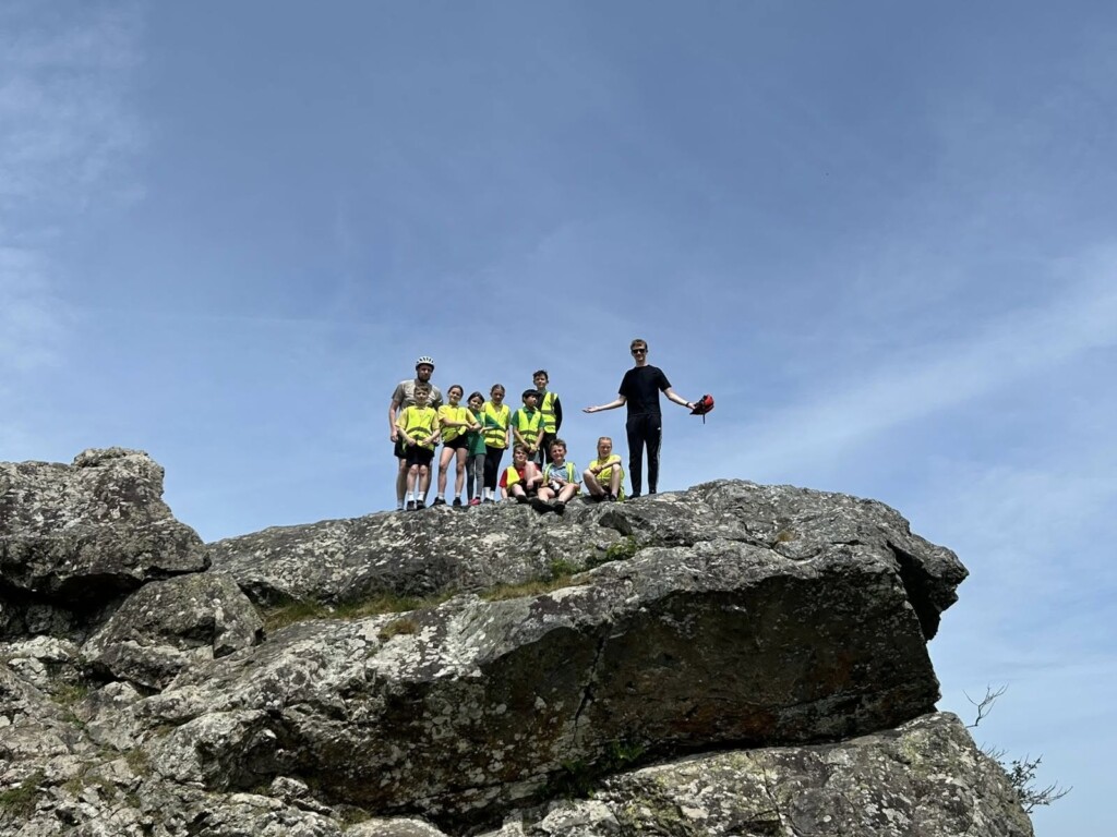 Students and staff on top of a big rock