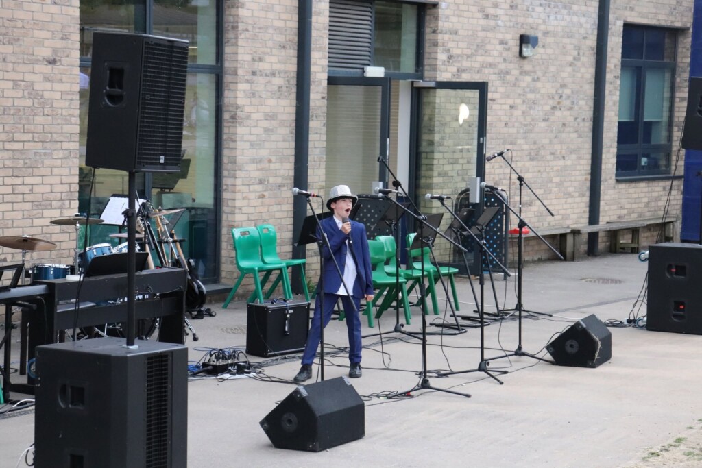 A student in a blue suit and silver hat performing.