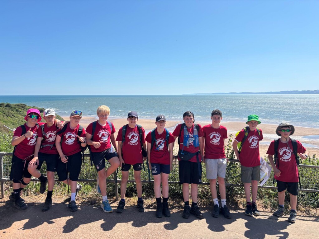 a group of pupils smiling for a photo with a beach in the background