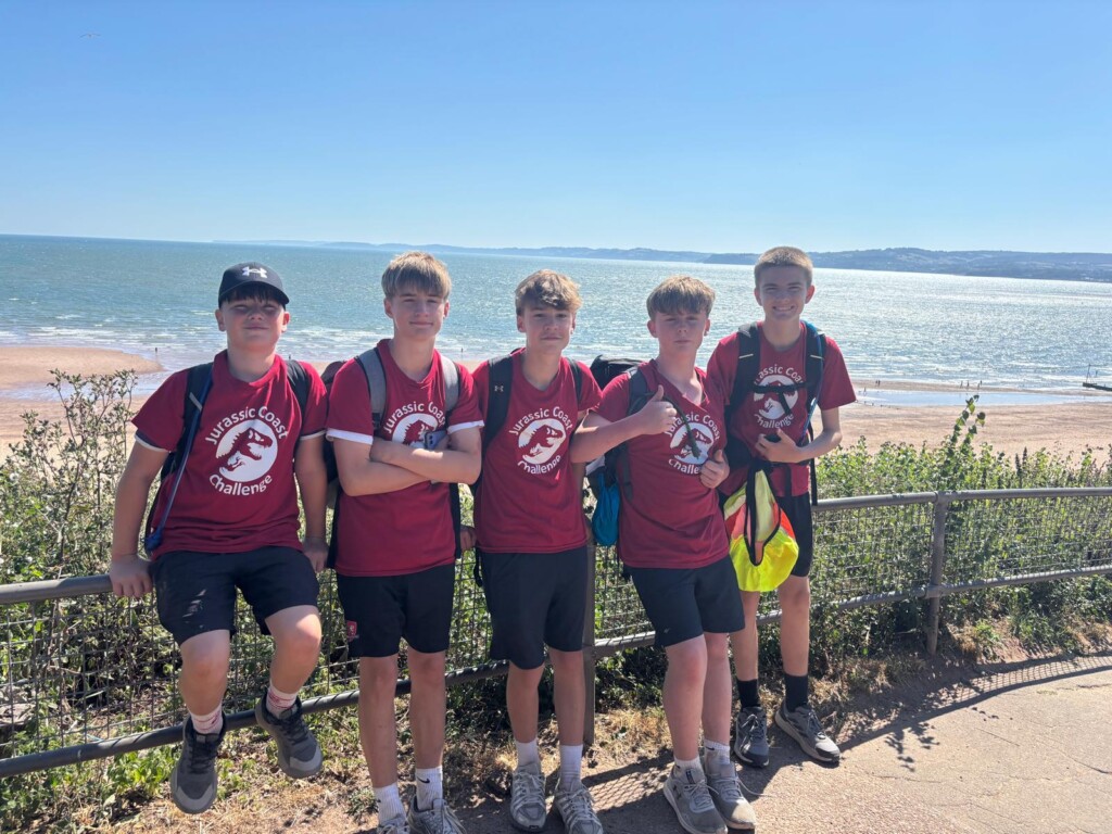 a group of students posing for a photo with the beach in the background