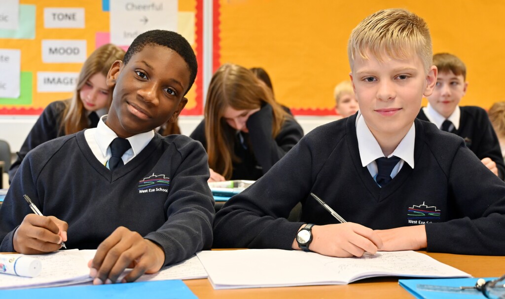 Two pupils sat at their desk smiling at the camera