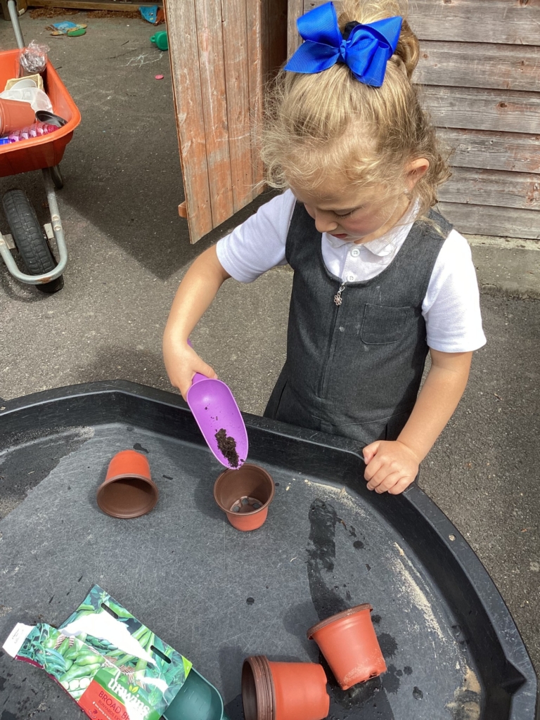 A pupil filling a pot with soil