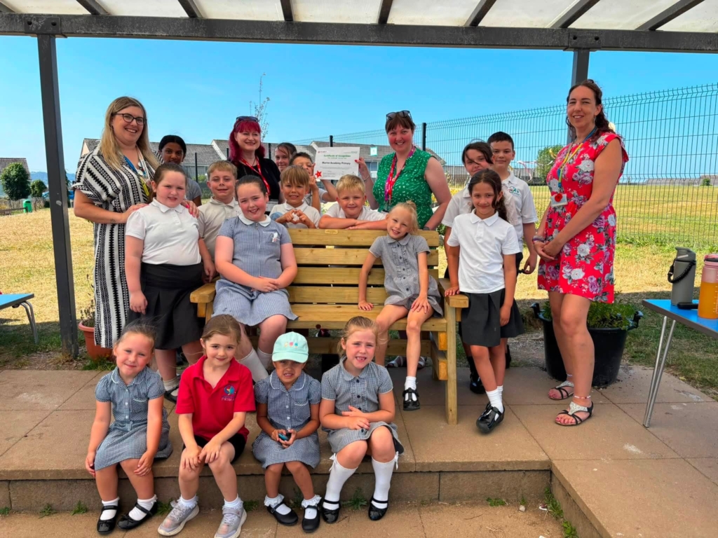 Students and staff smiling for a photo on their buddy bench