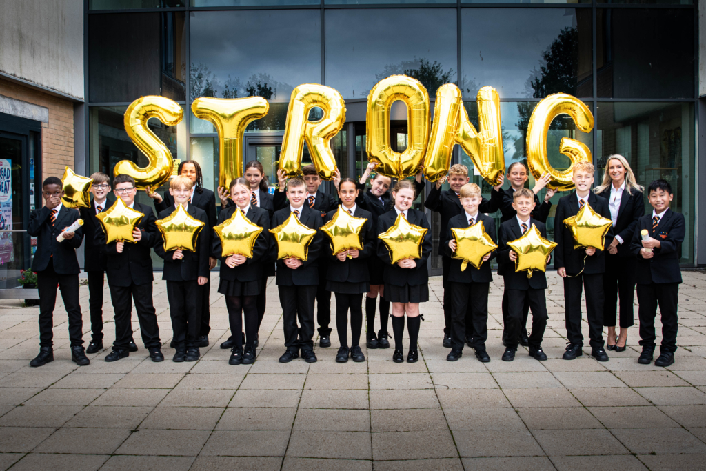 Students holding balloons that spell STRONG and star balloons