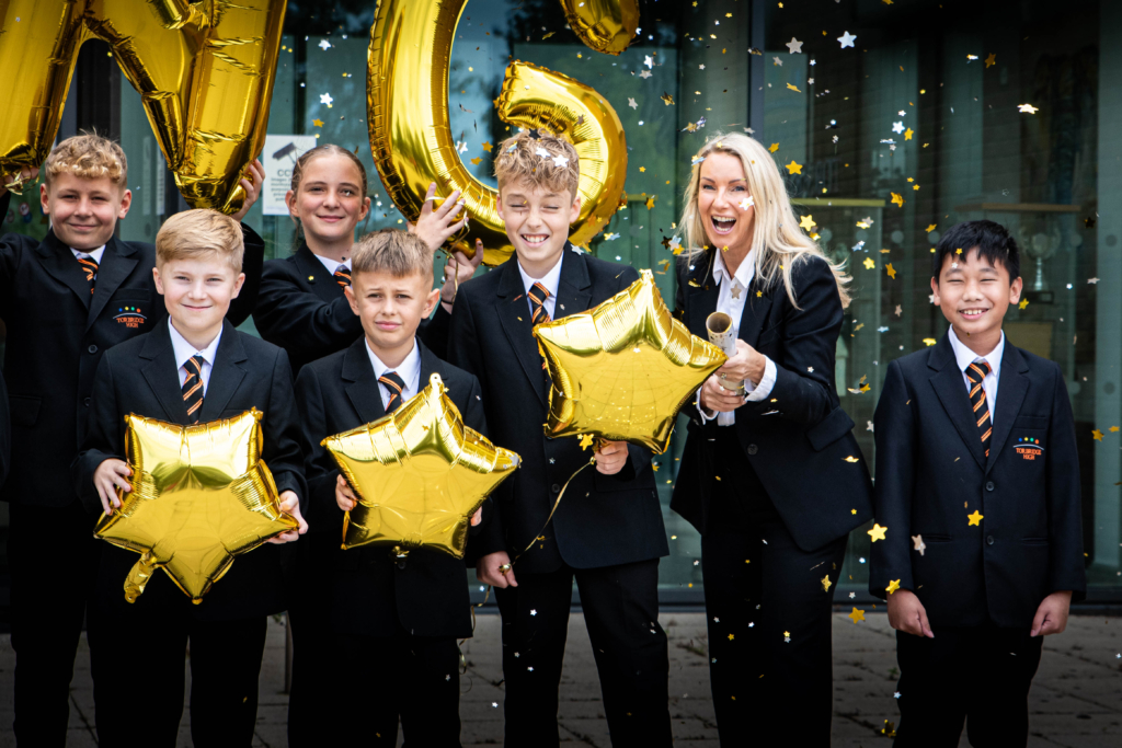 Headteacher Tracy popping confetti with students holding balloons and smiling