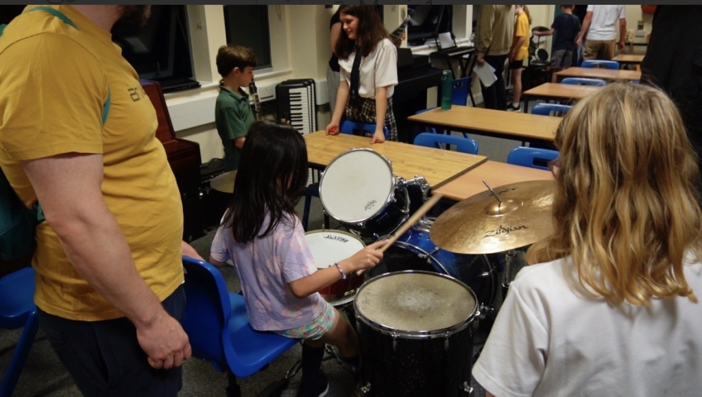 Visitors getting the chance to try music equipment, a girl playing the drums is pictured