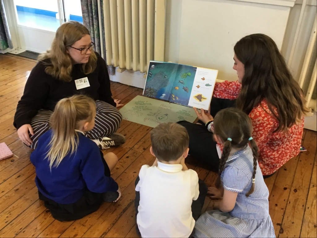 Trainee teachers reading to three pupils